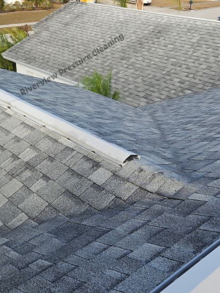 Close-up of a shingle roof with a metal flashing, showing weathering and signs of wear.