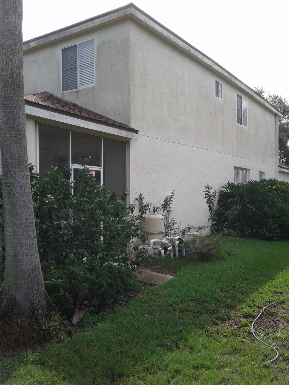Two-story beige house with a small covered porch and green lawn beside it