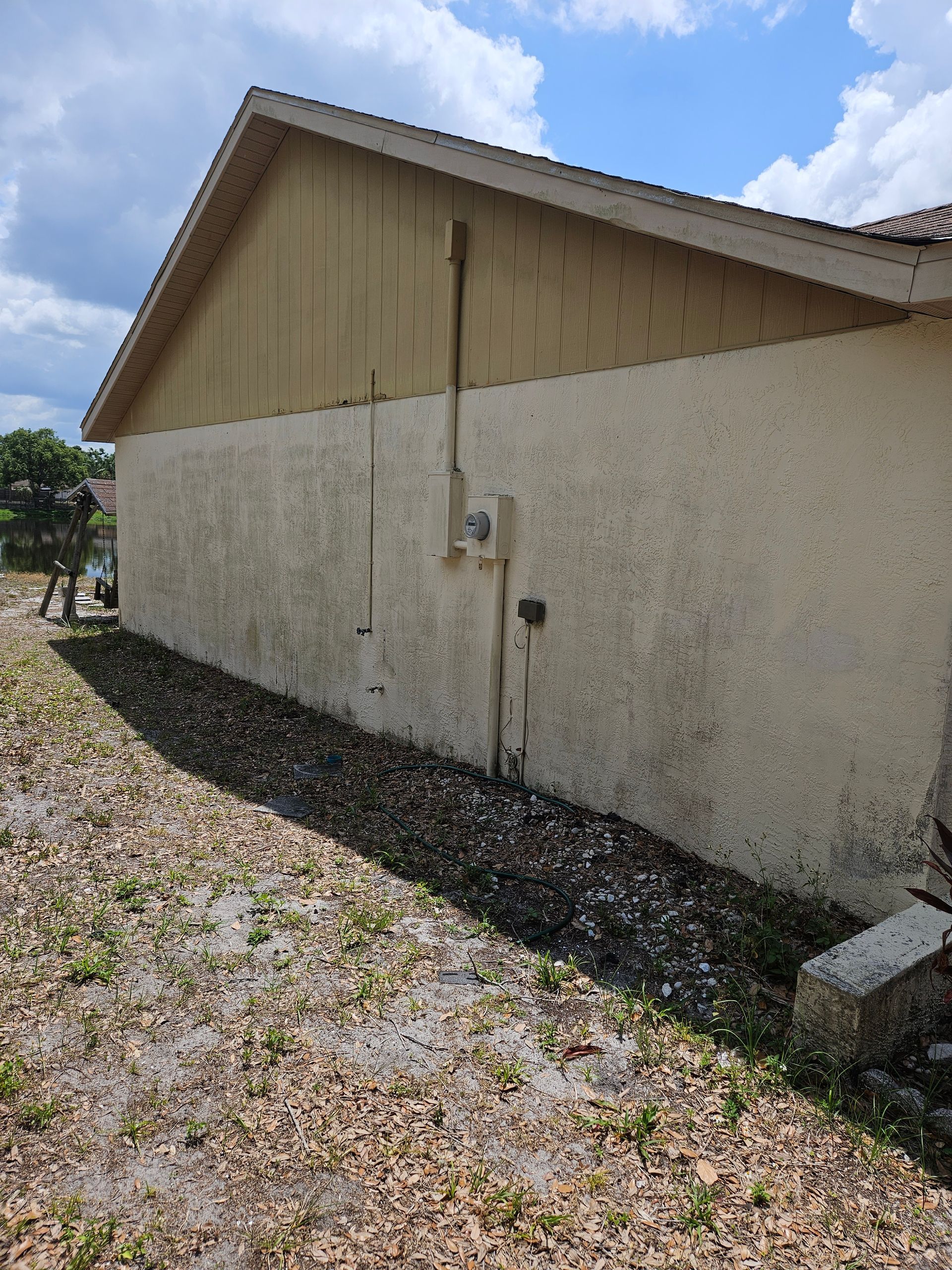 Green algae and mold on side of house in Riverview, FL. House pressure washing removes algae, mold and dirt.