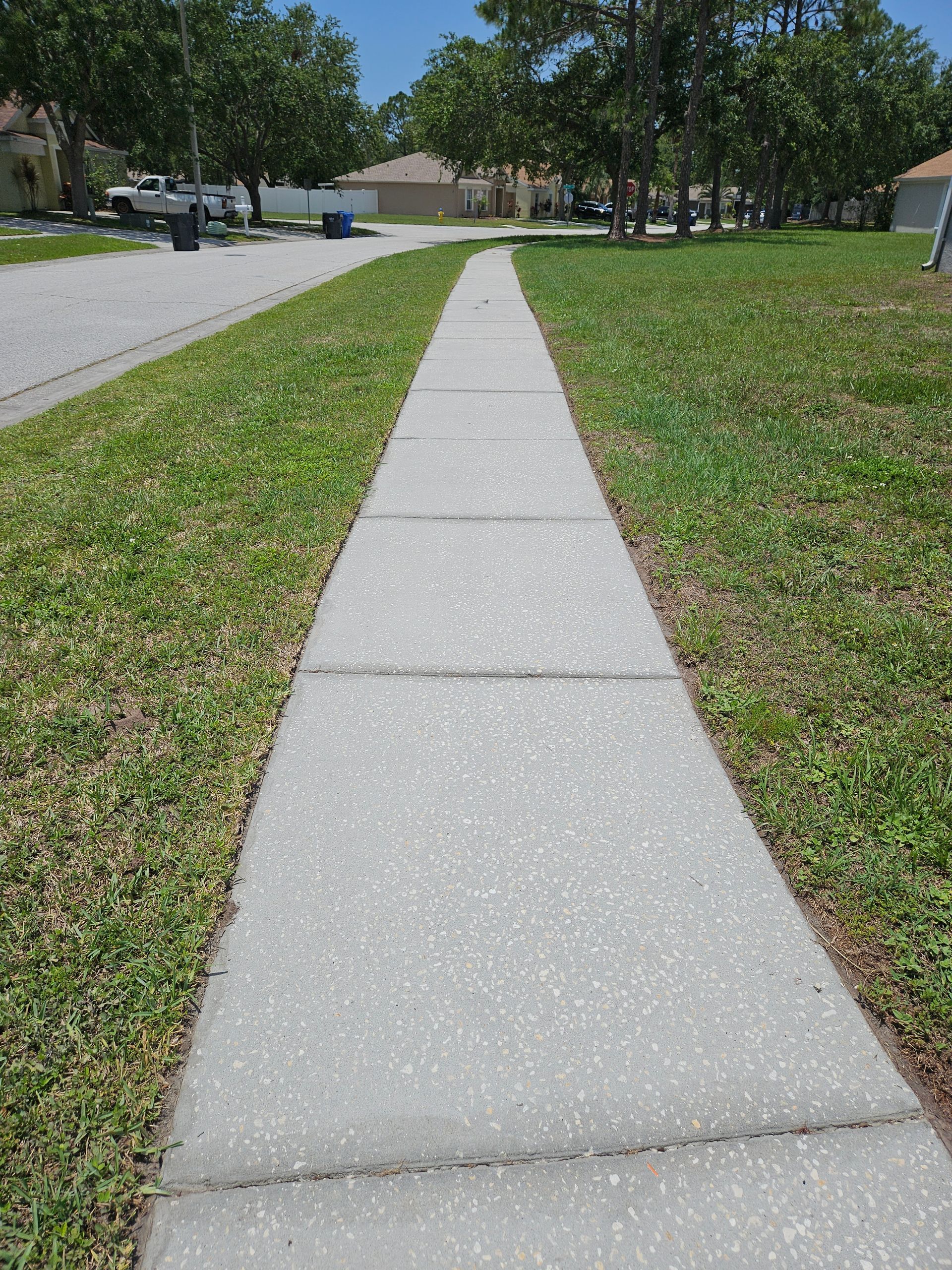 A concrete sidewalk leading to a grassy field