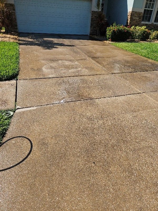 Concrete driveway leading to a blue garage, with a garden hose on the left side.