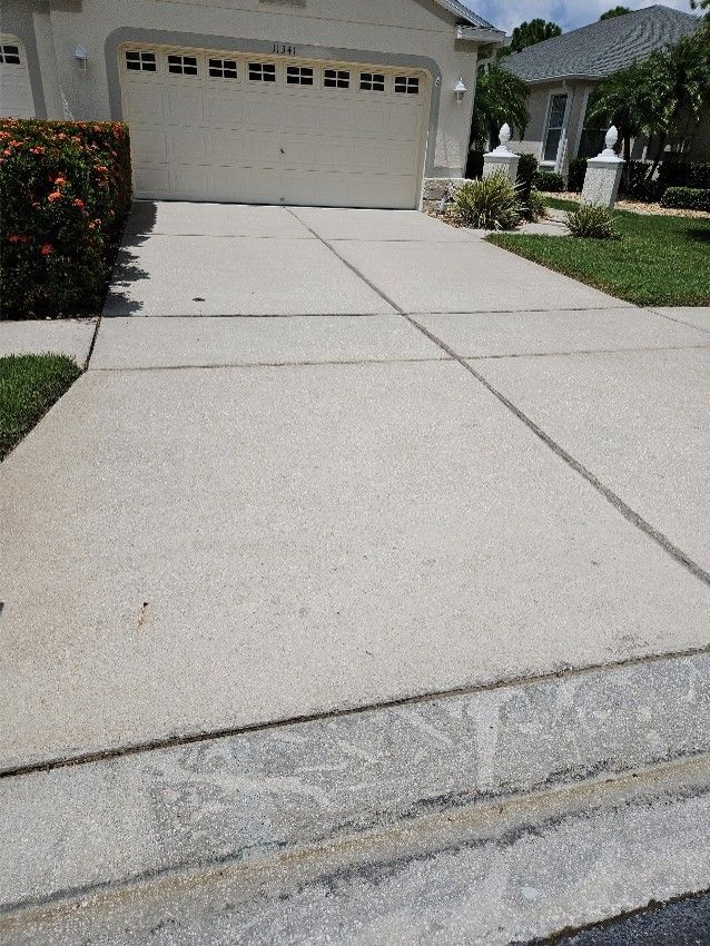 Concrete driveway leading to a beige garage in a suburban home driveway.