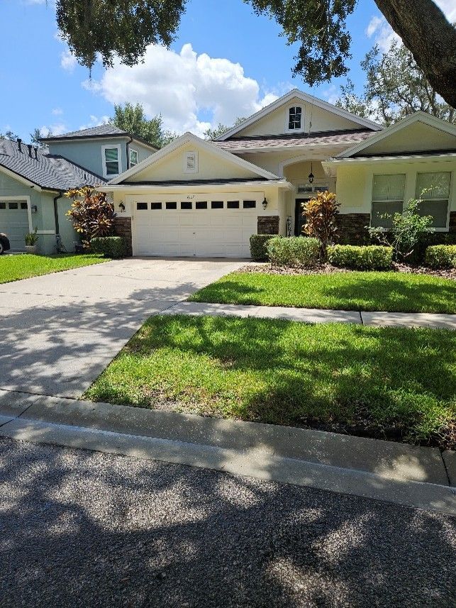 Suburban house with white garage, driveway, and green lawn under a blue sky