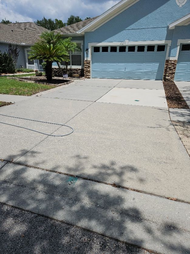 Suburban house driveway with a blue garage door and a concrete driveway in sunlight