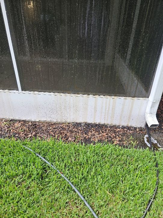Screened porch wall with white base, mulch strip, and green grass in the foreground