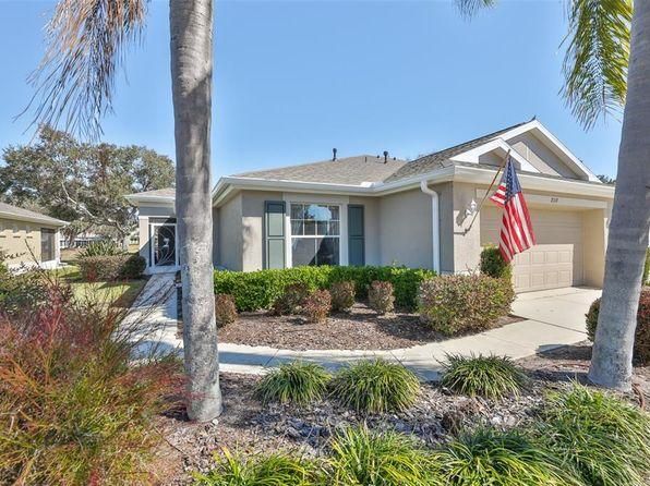 Single-story suburban house with a garage, front yard shrubs, and an American flag by the driveway