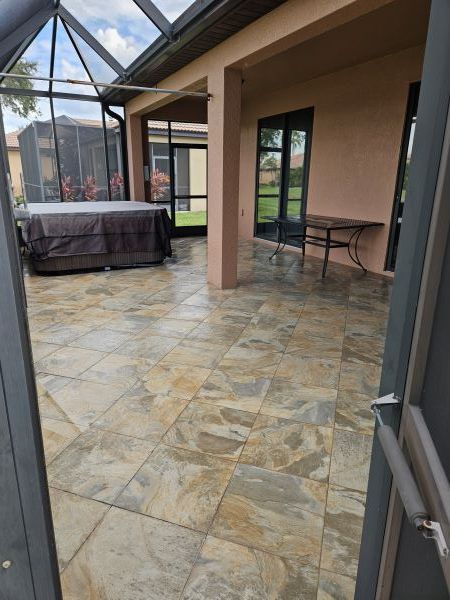 Covered patio with stone tile floor, screened enclosure, and outdoor table and chairs.