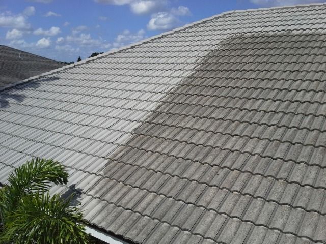 Roof partially cleaned, showing contrast between dirty and cleaned tile sections under a blue sky.
