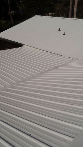 White corrugated metal roof on a building, with a second roof section visible.