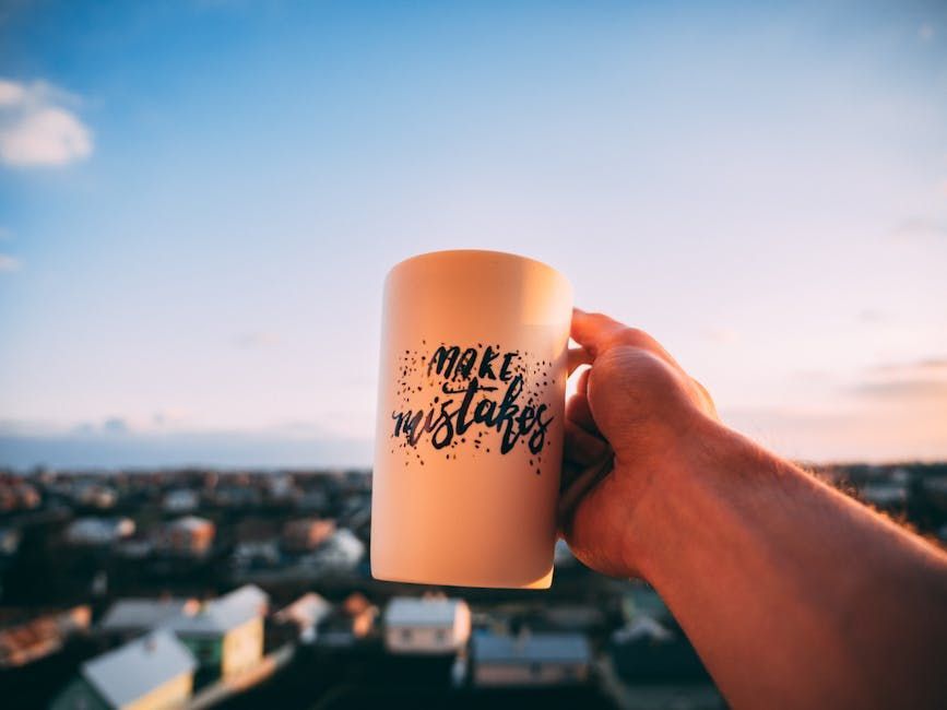 A person is holding a mug that says `` make my mistakes ''.