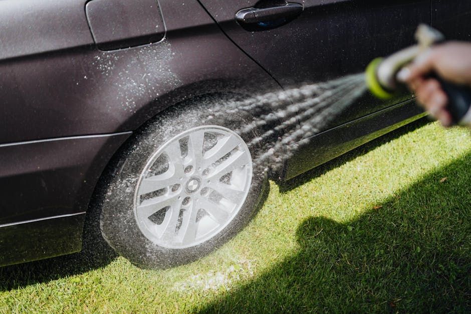 A person is washing a car with a hose.