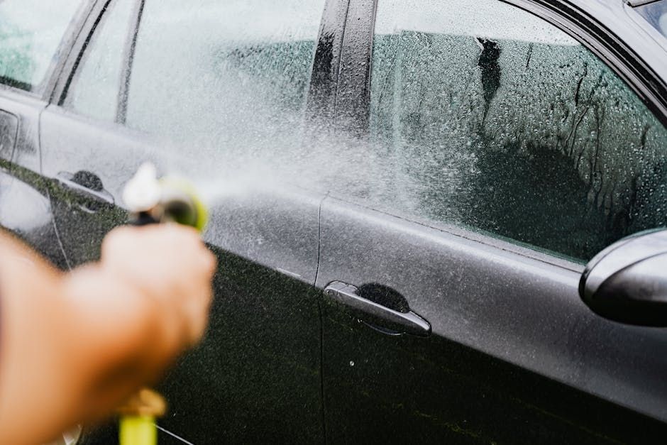 A person is washing a car with a hose.