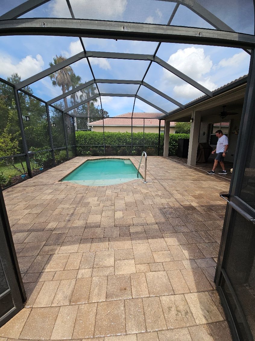 Screened pool enclosure with a small turquoise pool and a person standing by the patio.