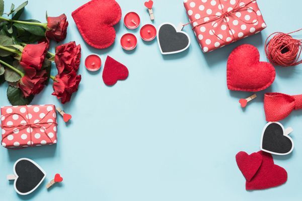 a blue background with red hearts , roses , gifts and candles .