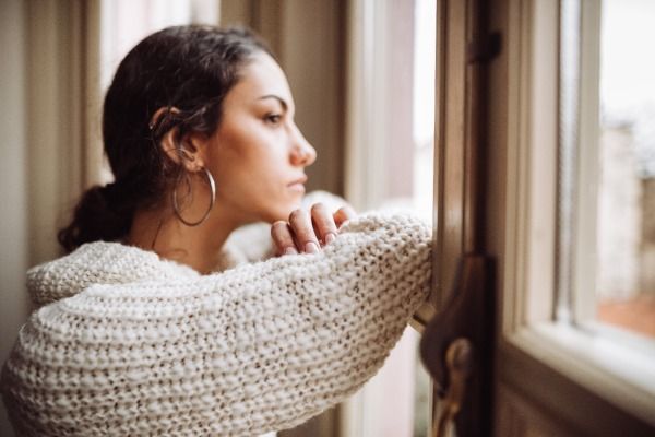 a woman in a sweater is looking out of a window .