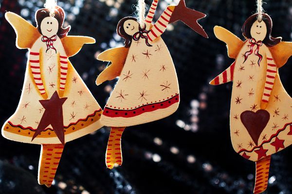 three angels are hanging from a string on a christmas tree