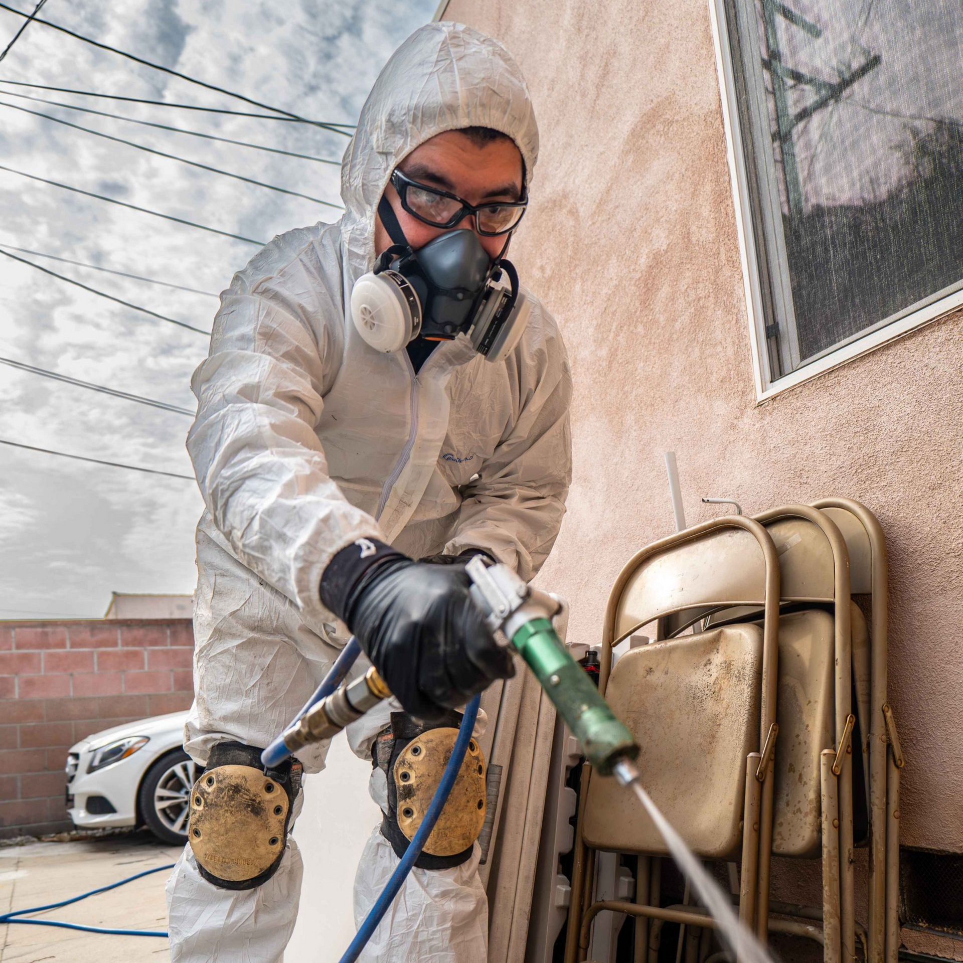 Person in protective suit spraying insecticide.