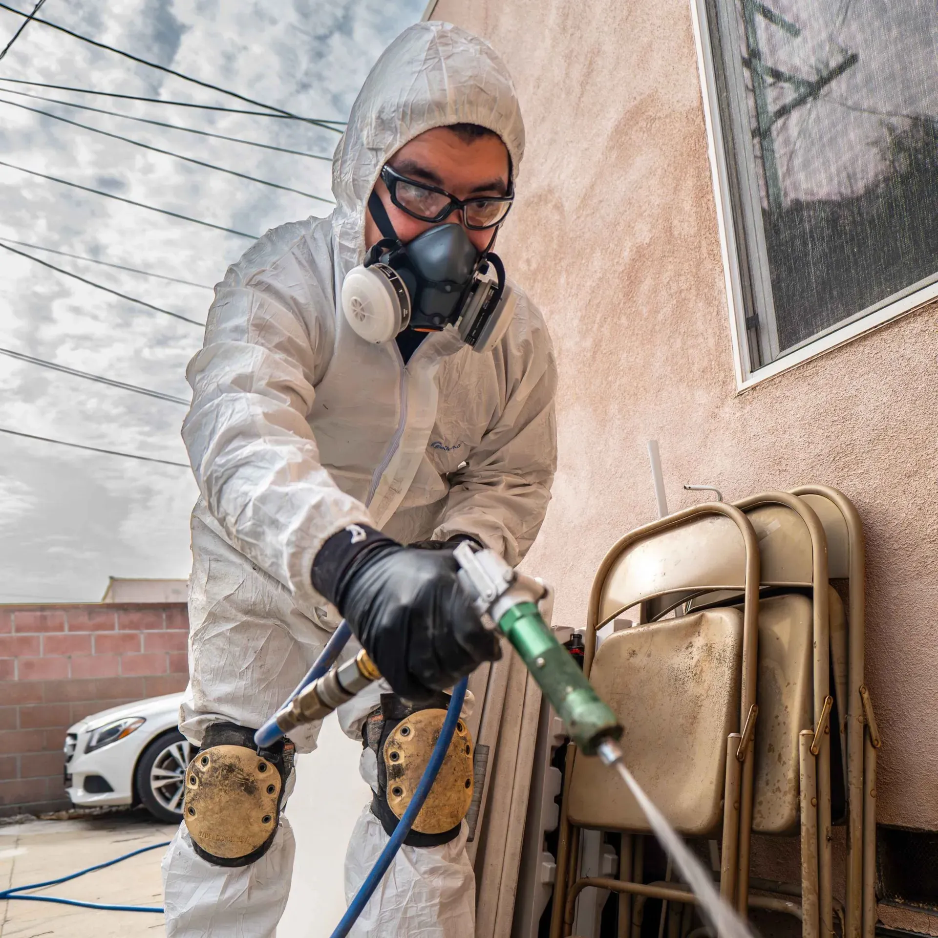 Person in protective suit spraying insecticide.
