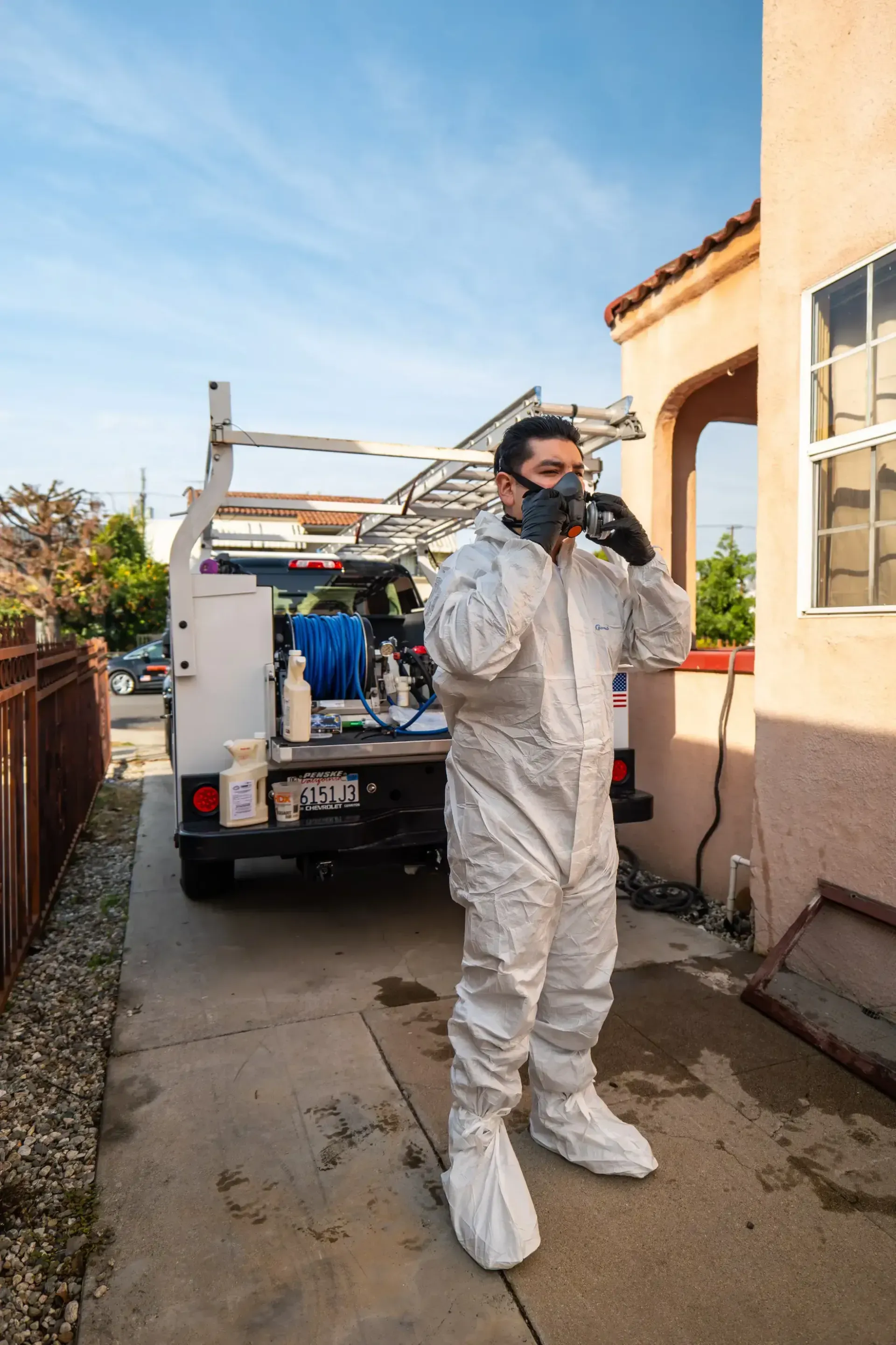 A man in a protective suit is standing in front of a truck.