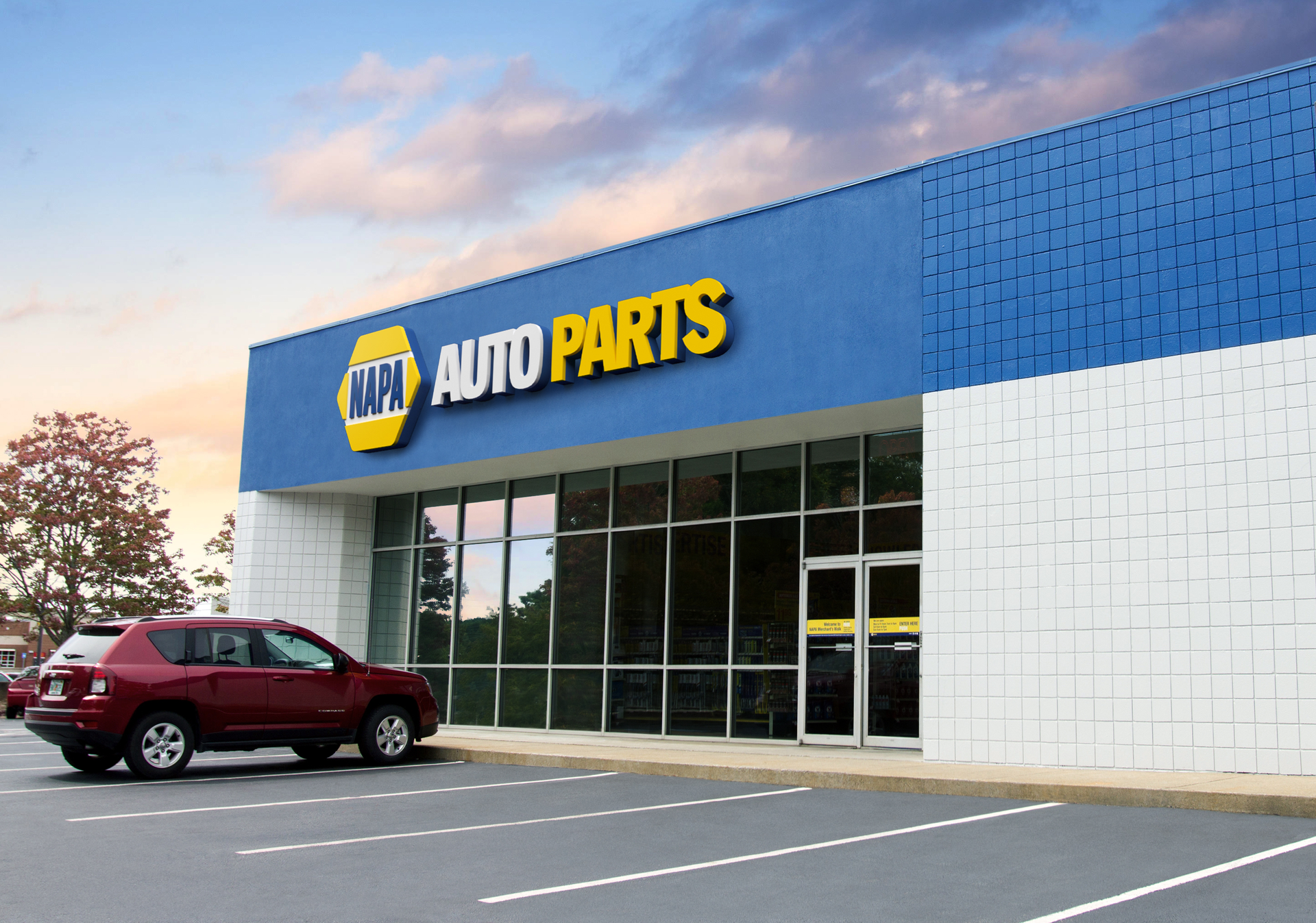 NAPA Auto Parts store with a red SUV parked in front. Blue and yellow building, daytime.