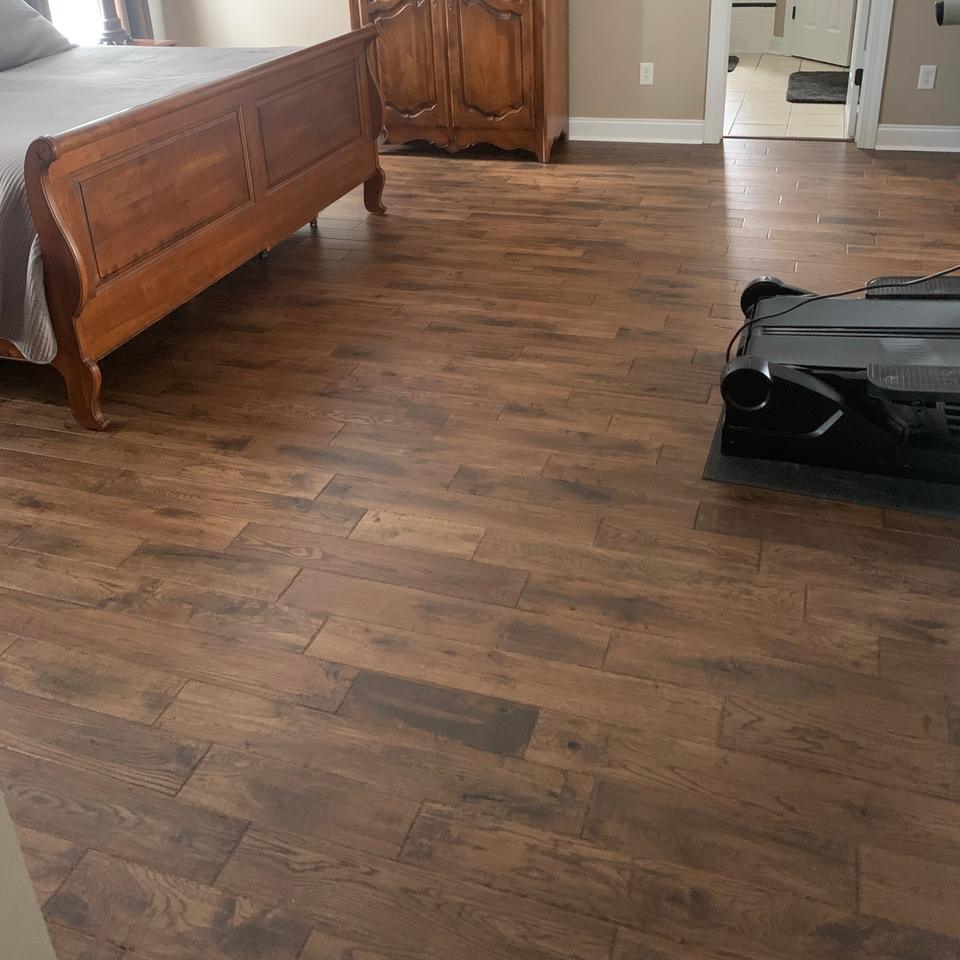 A bedroom with hardwood floors , a bed and a treadmill.