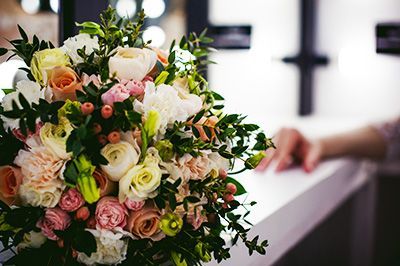 Mixed bouquet of cream, pink, and peach flowers on a white table at a wedding ceremony