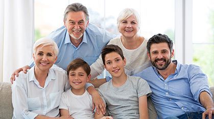 Smiling family sitting together on a couch in a bright living room.