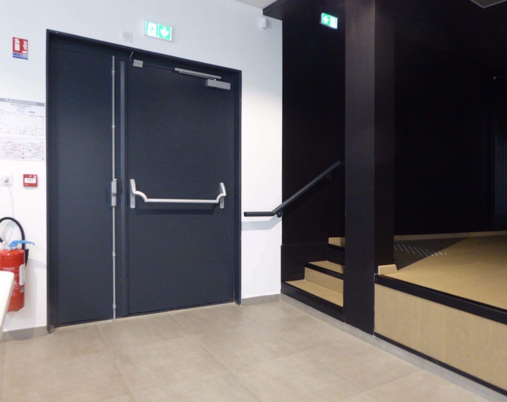 A hallway with two black doors and stairs