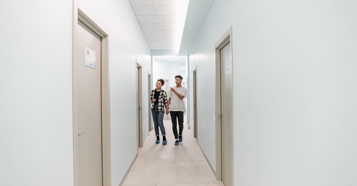 A man and a woman are walking down a hallway.