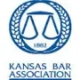 A logo for the kansas bar association with a scale of justice in a circle.