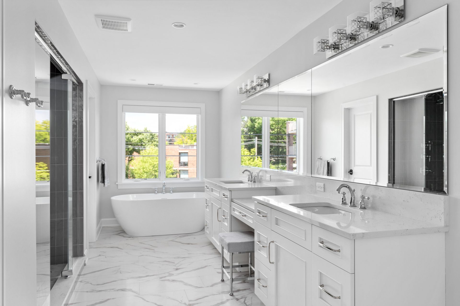 A bathroom with two sinks , a tub , and a mirror.