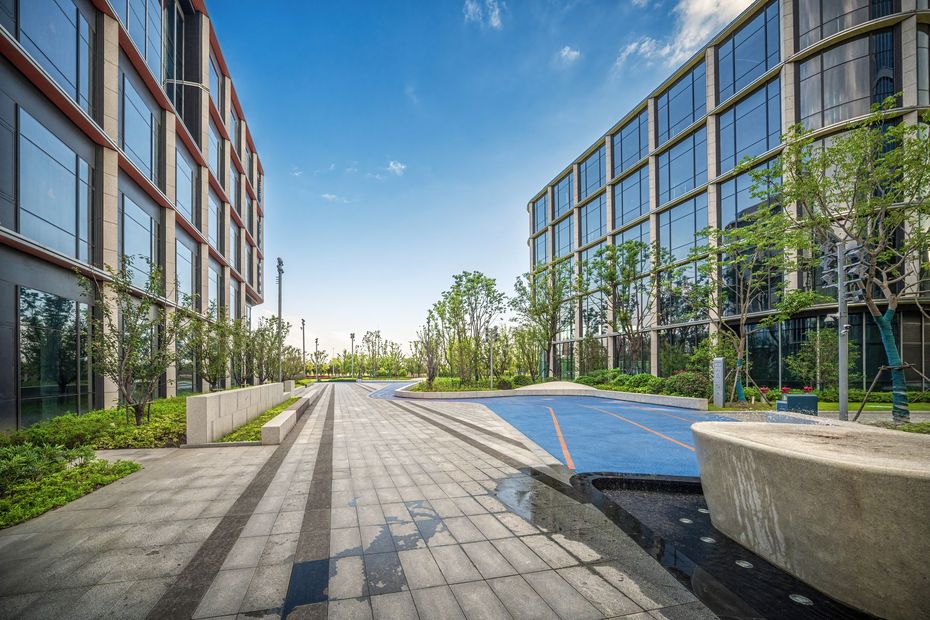 A large building with a lot of windows is surrounded by trees and a brick walkway.