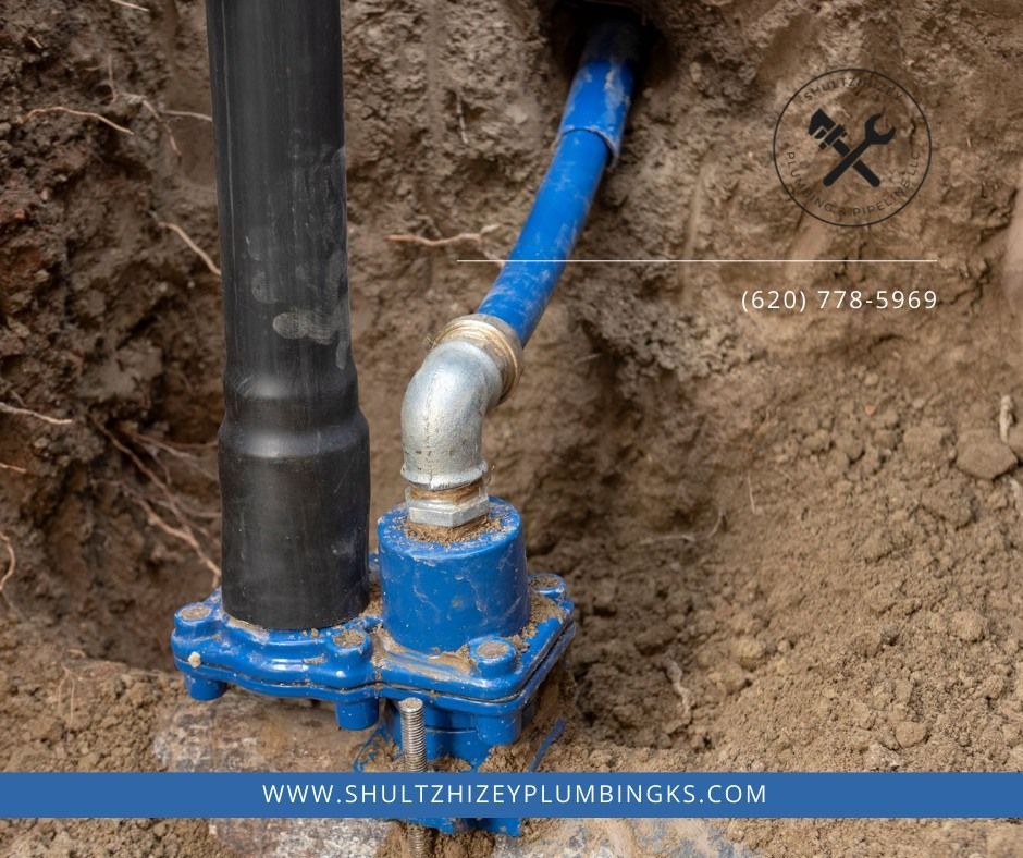 Blue plumbing components exposed in dirt, with black pipe and logo.