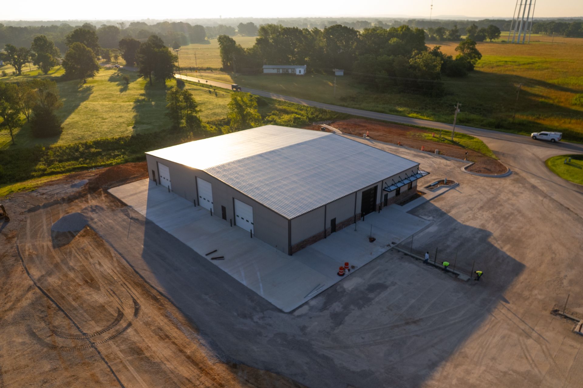 Aerial view of gray industrial metal building with garage doors in rural setting with fields and trees