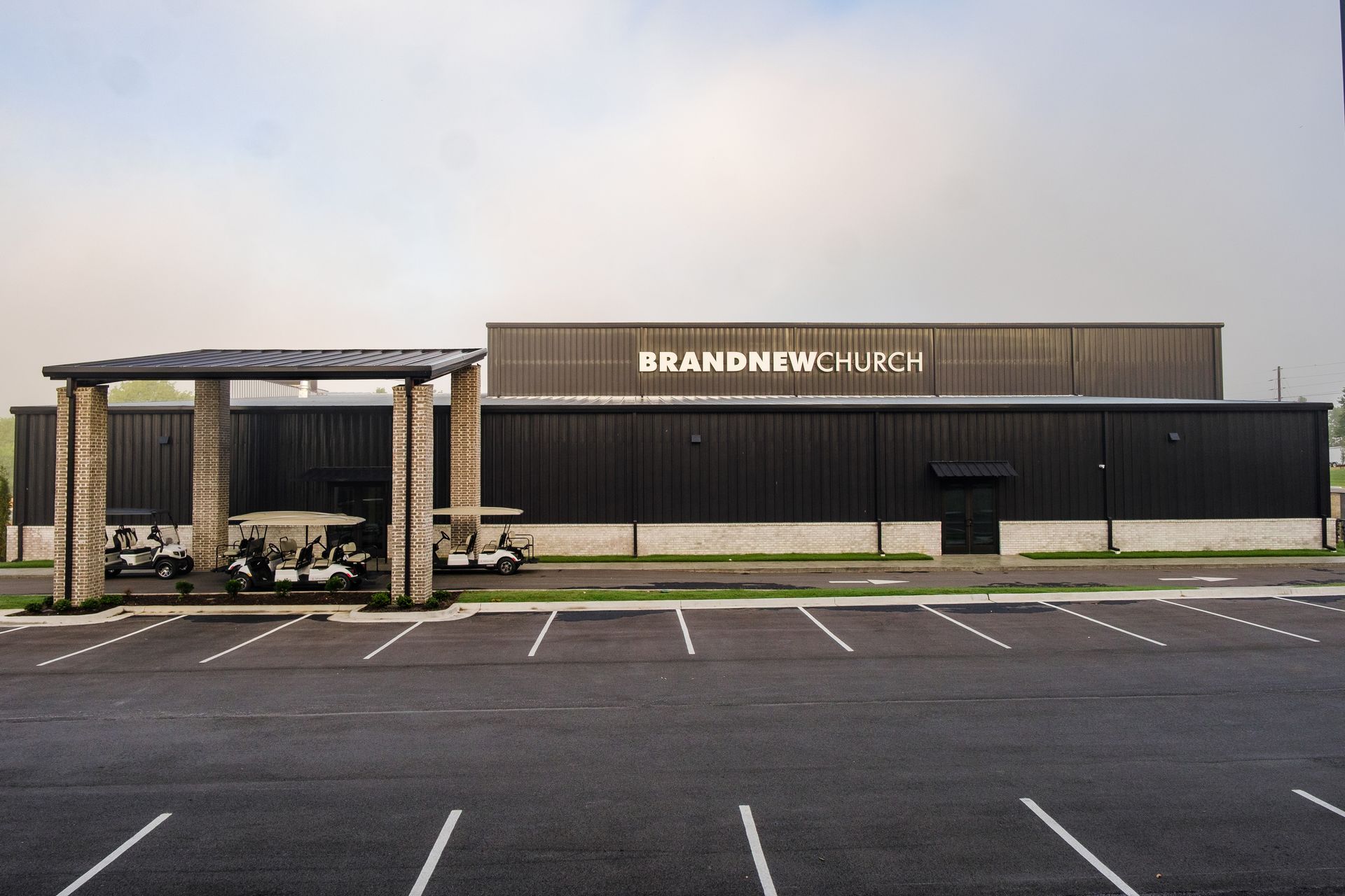 Exterior of BrandNew Church building with covered golf cart parking and white signage