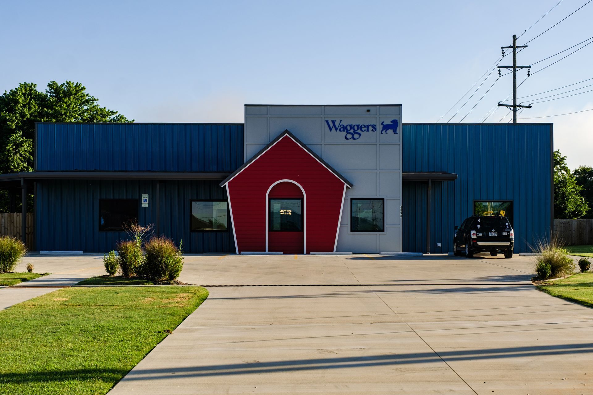 Waggers dog facility with red doghouse entrance, blue and gray building, and SUV outside