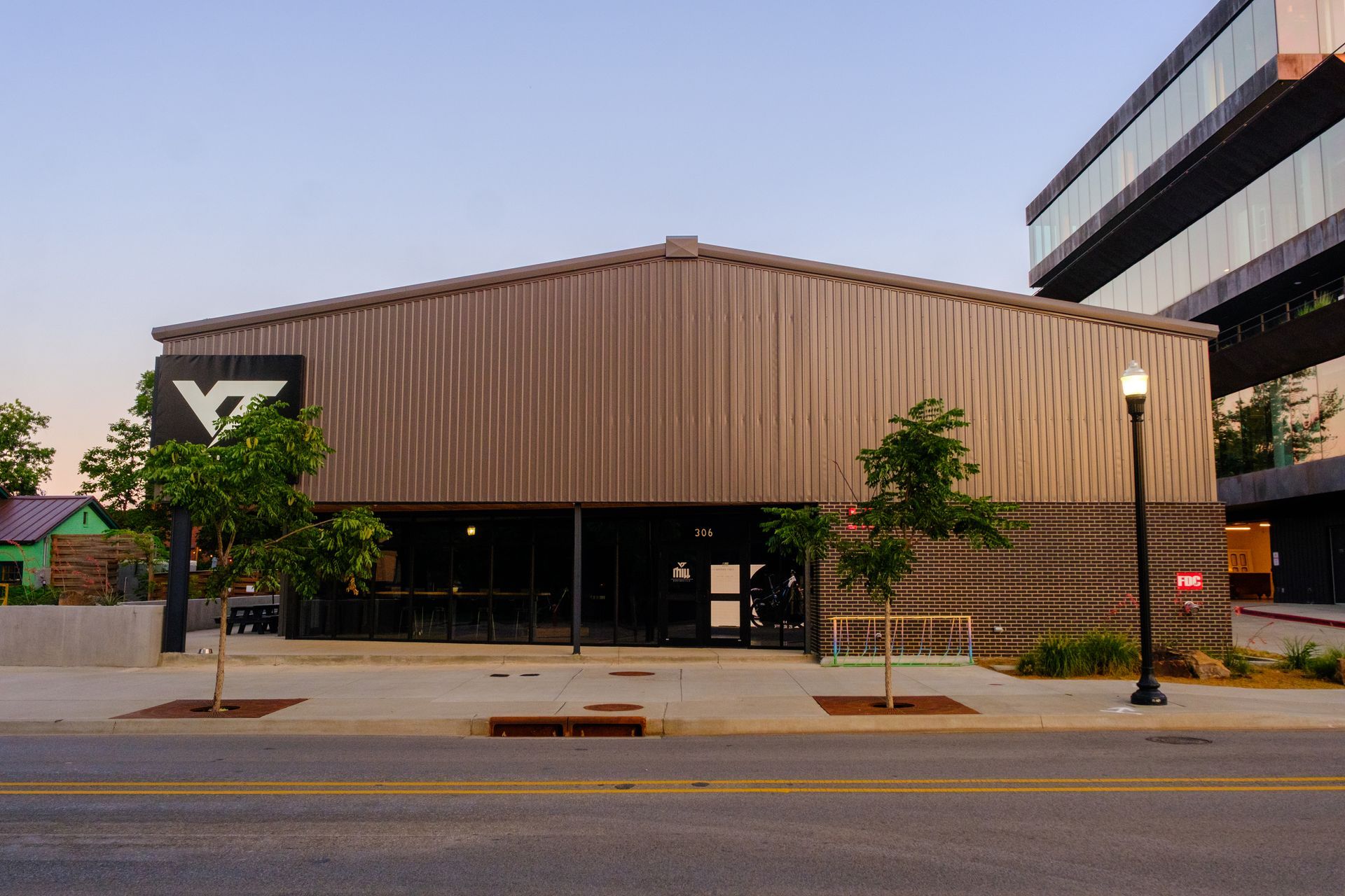 Modern biking facility with wood siding, large windows, and geometric logo on city street
