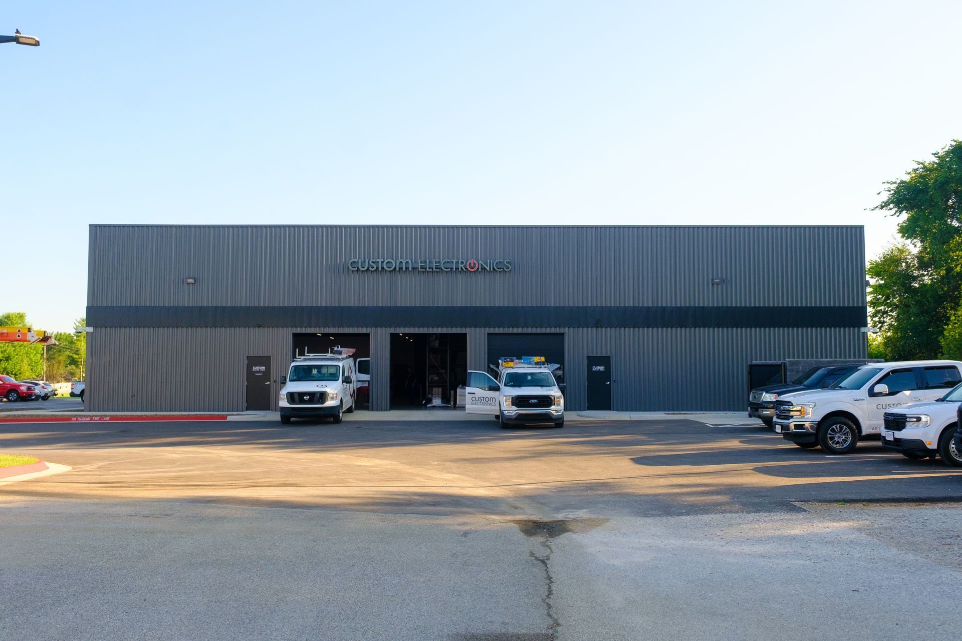 Gray metal business with open garage bays, service vehicles, and Tracer signage on building