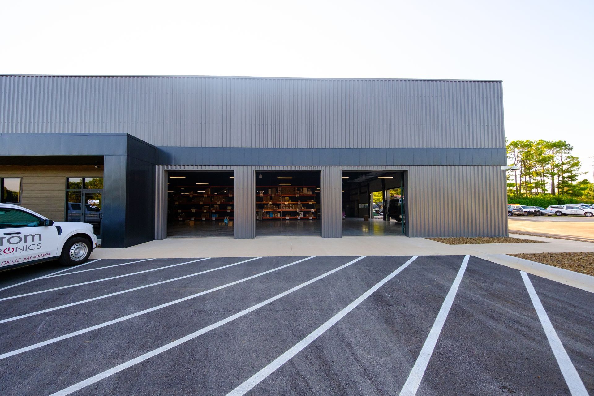 Gray metal building with open garage doors showing gym equipment and white truck parked outside