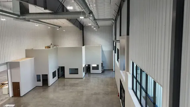 High-angle view of a bright, modern, industrial warehouse interior with white walls, concrete floors, and office units.