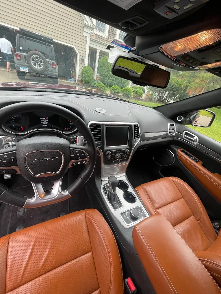 Luxurious car interior with tan leather seats, black dashboard, and silver center console.