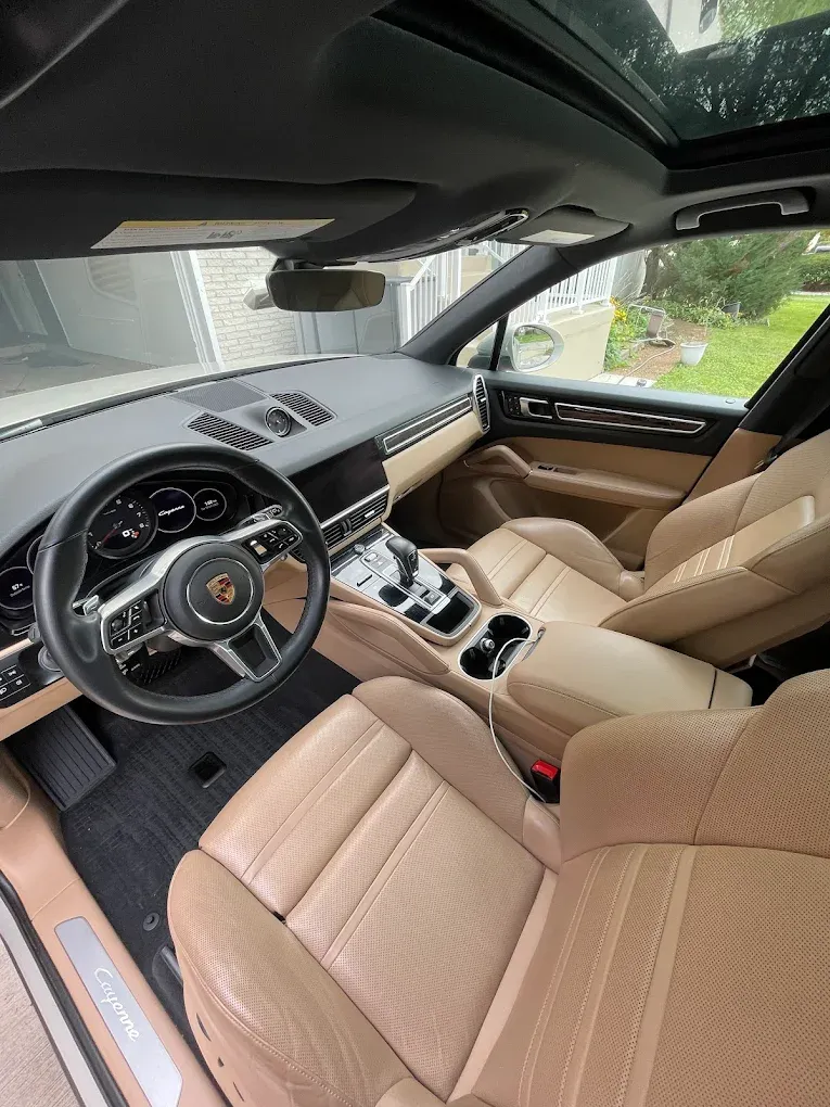 Tan leather car interior with steering wheel, center console, and sunroof view