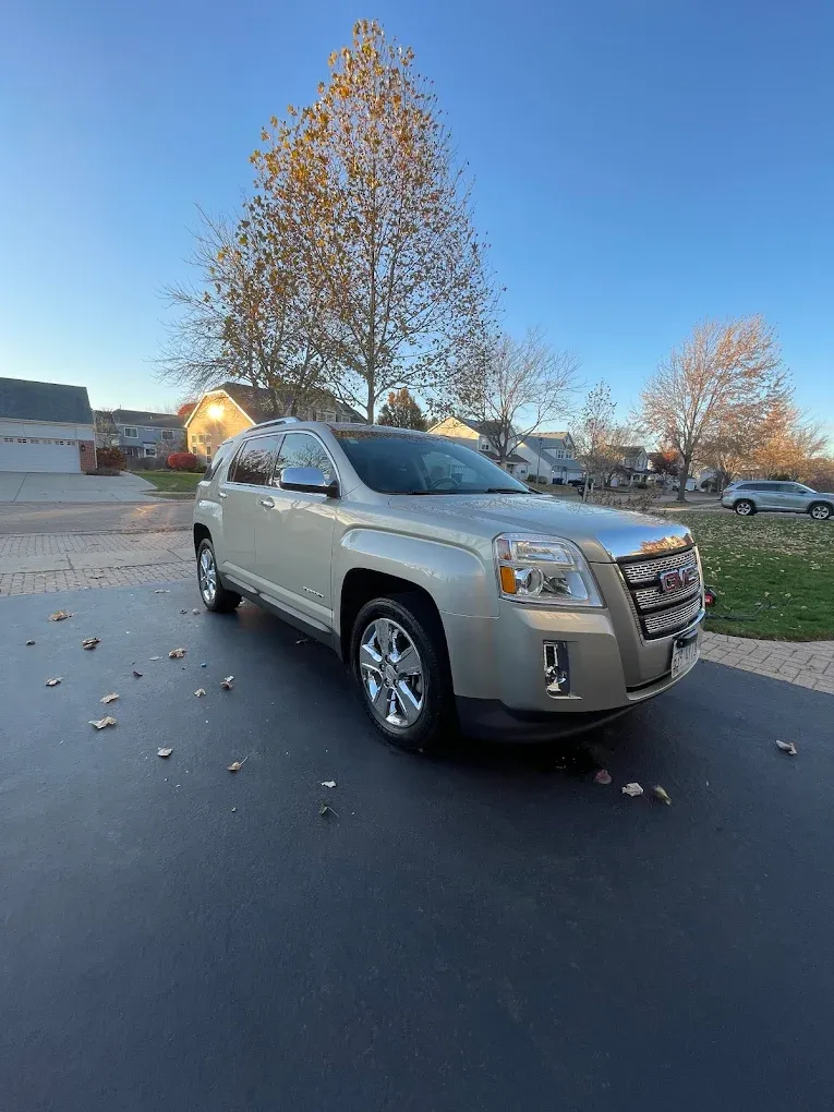 Silver SUV parked on a suburban street at sunset with leafless trees and scattered leaves on the pavement