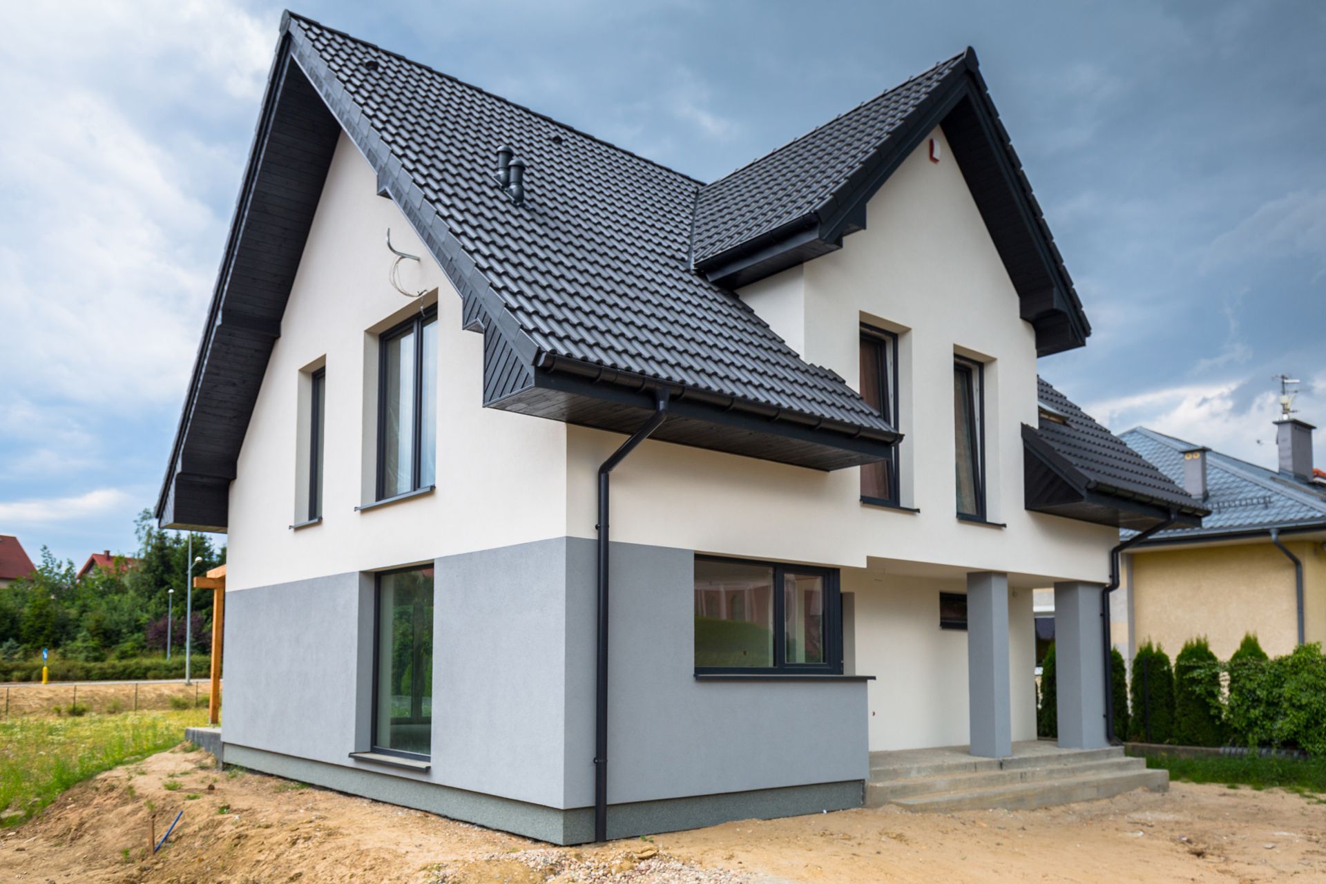 Modern white two-story house with dark gray roof and large windows on a grassy lot Modern white two-story house with dark gray roof and large windows on a grassy lot