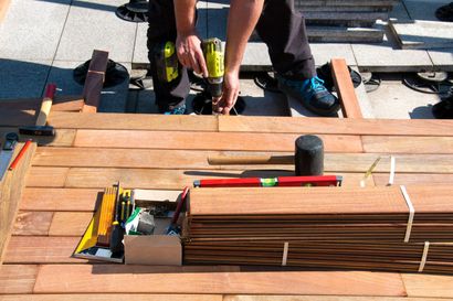 Tools and wooden slats on a boat deck, with a person working in the background