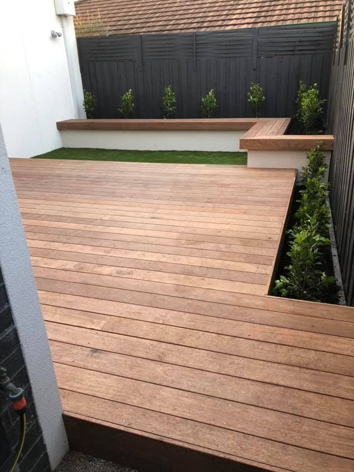 Wooden deck with built-in planter boxes, green grass area, and black fence in a backyard — MGP Landscaping in Geelong, VIC