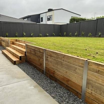 Wooden retaining wall with steps, gravel bed, and grassy backyard — MGP Landscaping in Geelong, VIC