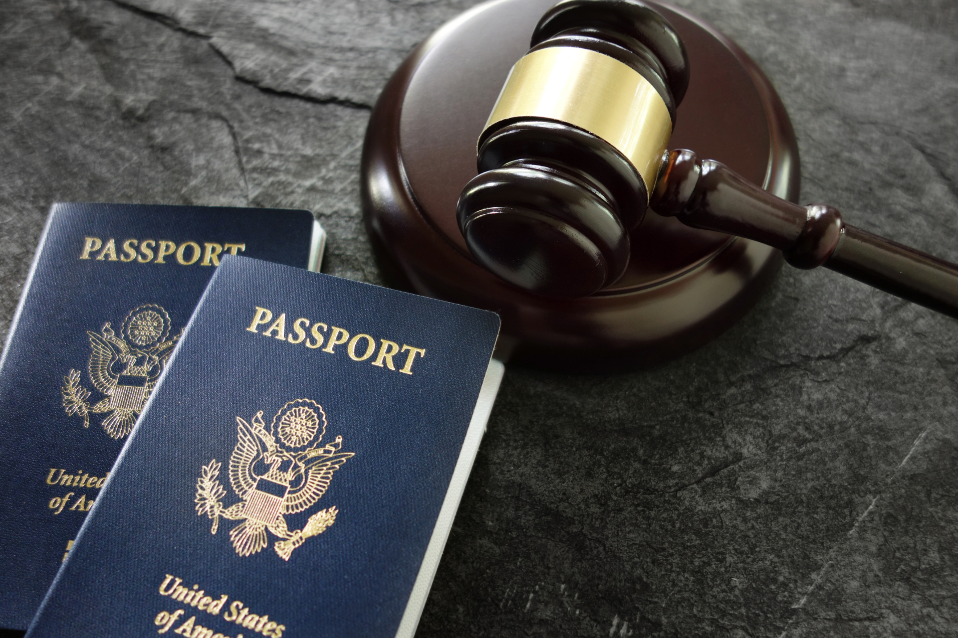 Two passports beside a judge’s gavel on a dark table