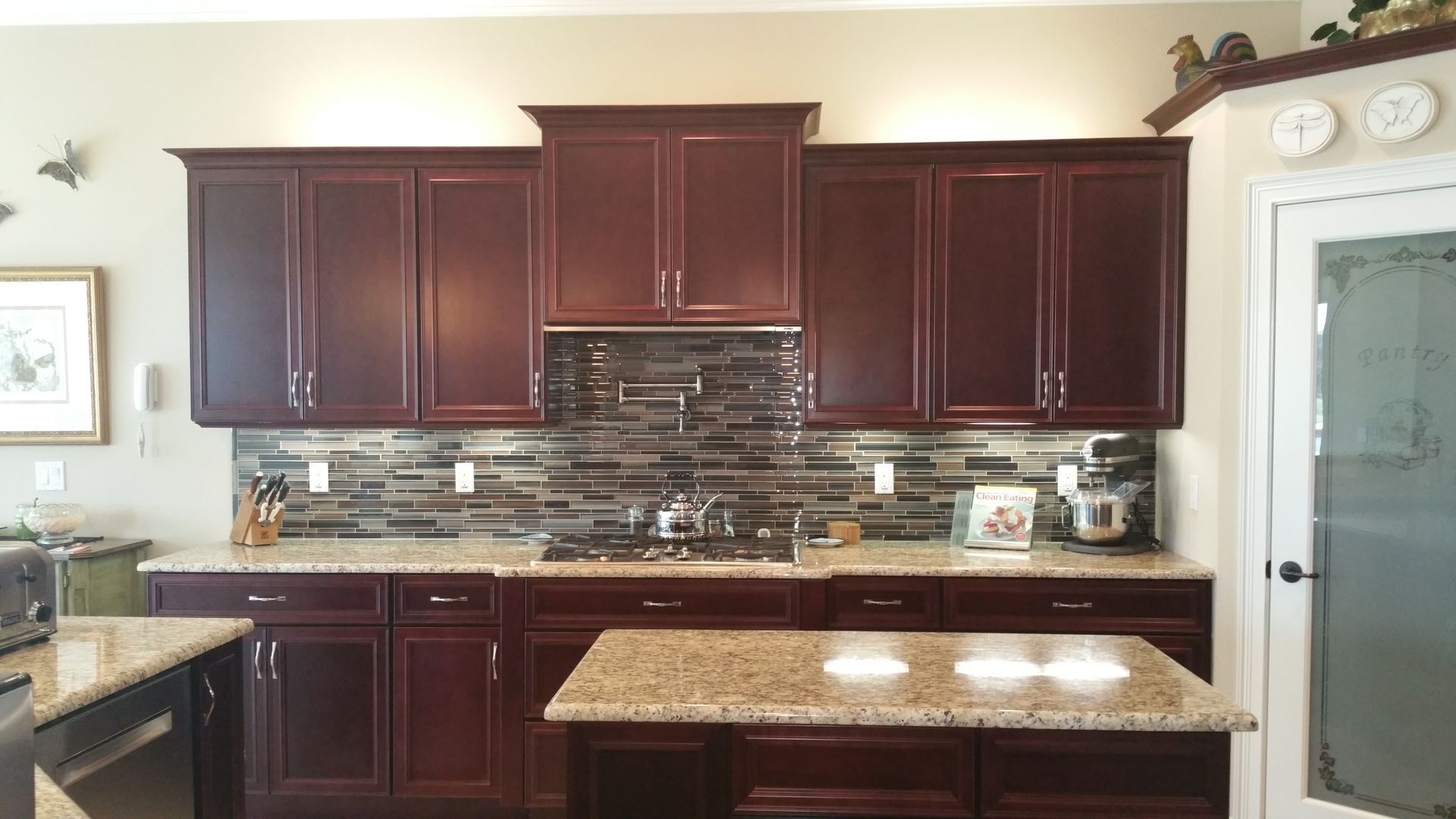Kitchen with dark wood cabinets, mosaic backsplash, and a light countertop island.