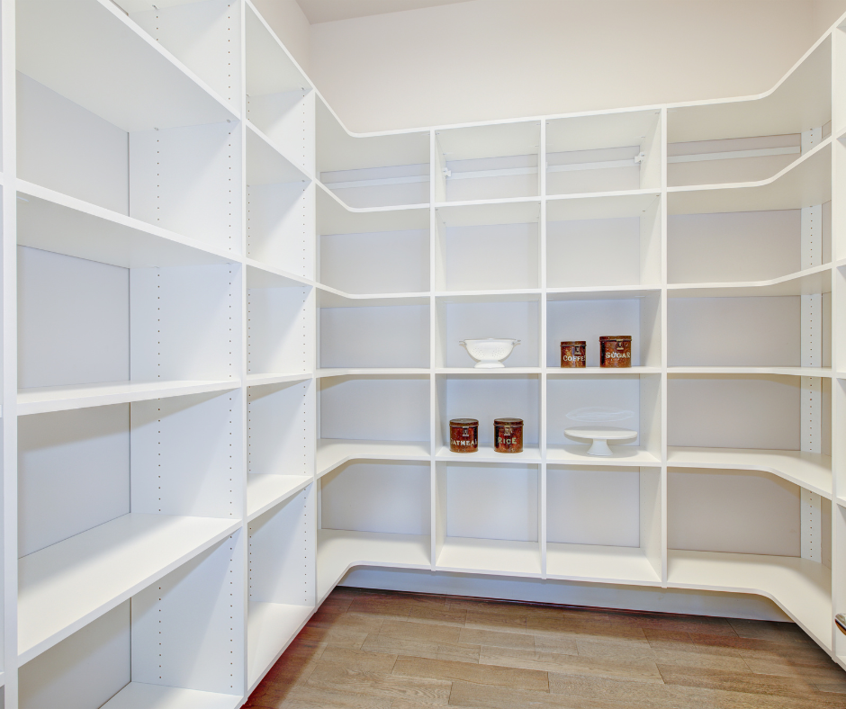 Bright white walk-in closet with built-in shelving and a wood floor, mostly empty with a few bowls and tins.